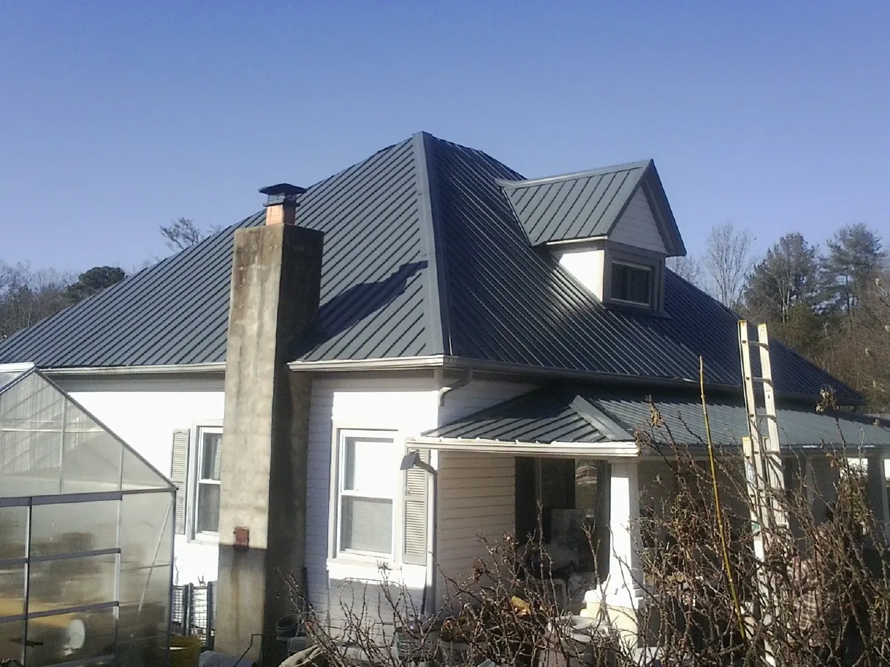 Dark blue standing seam metal roof on a white farmhouse with dormer — Slate & Tile Roof Repair by Roofing Brothers in Ophiem