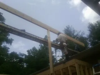 Carpenter setting a ridge beam over a new addition frame — Ice Dam Removal by Roofing Brothers in Ophiem