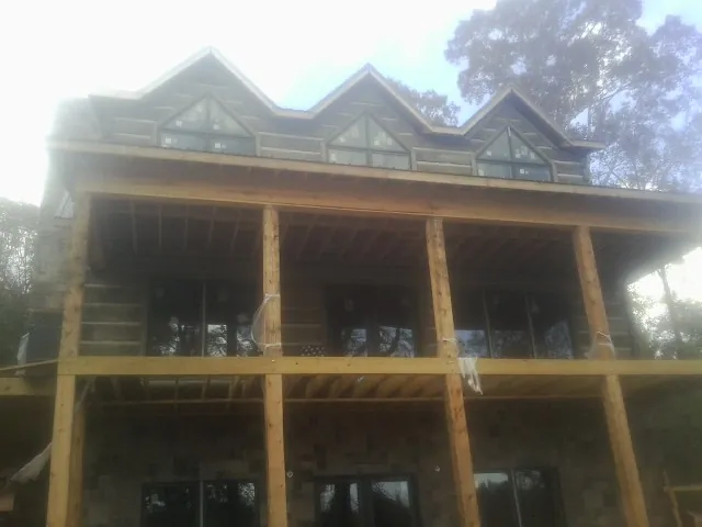 Dormers and porch framing on a large log home under construction — Roof Coating work by our crew in Ophiem