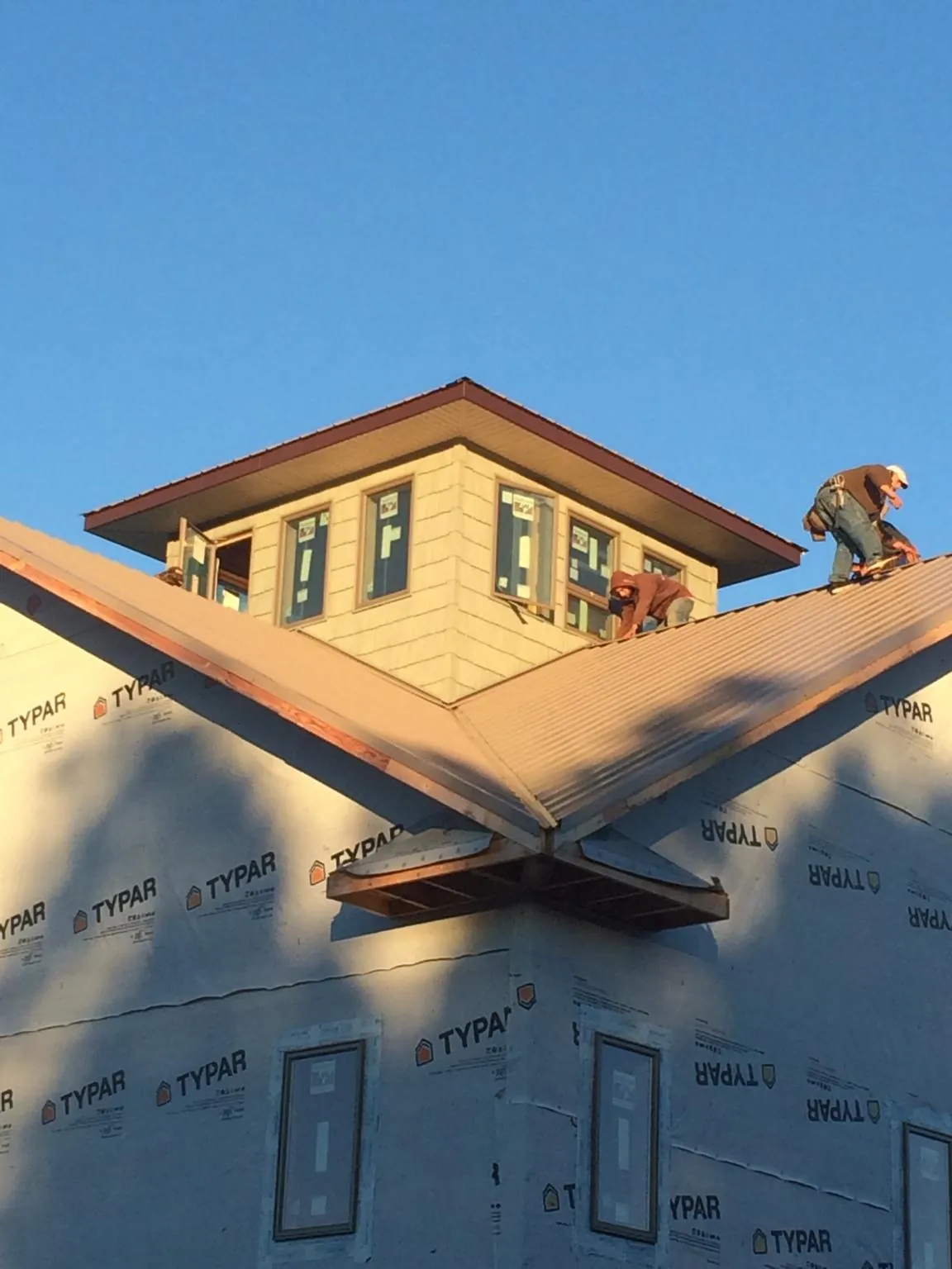 Roofers working around a rooftop cupola on a new metal roof at sunset — Roof Waterproofing in Ophiem by Roofing Brothers